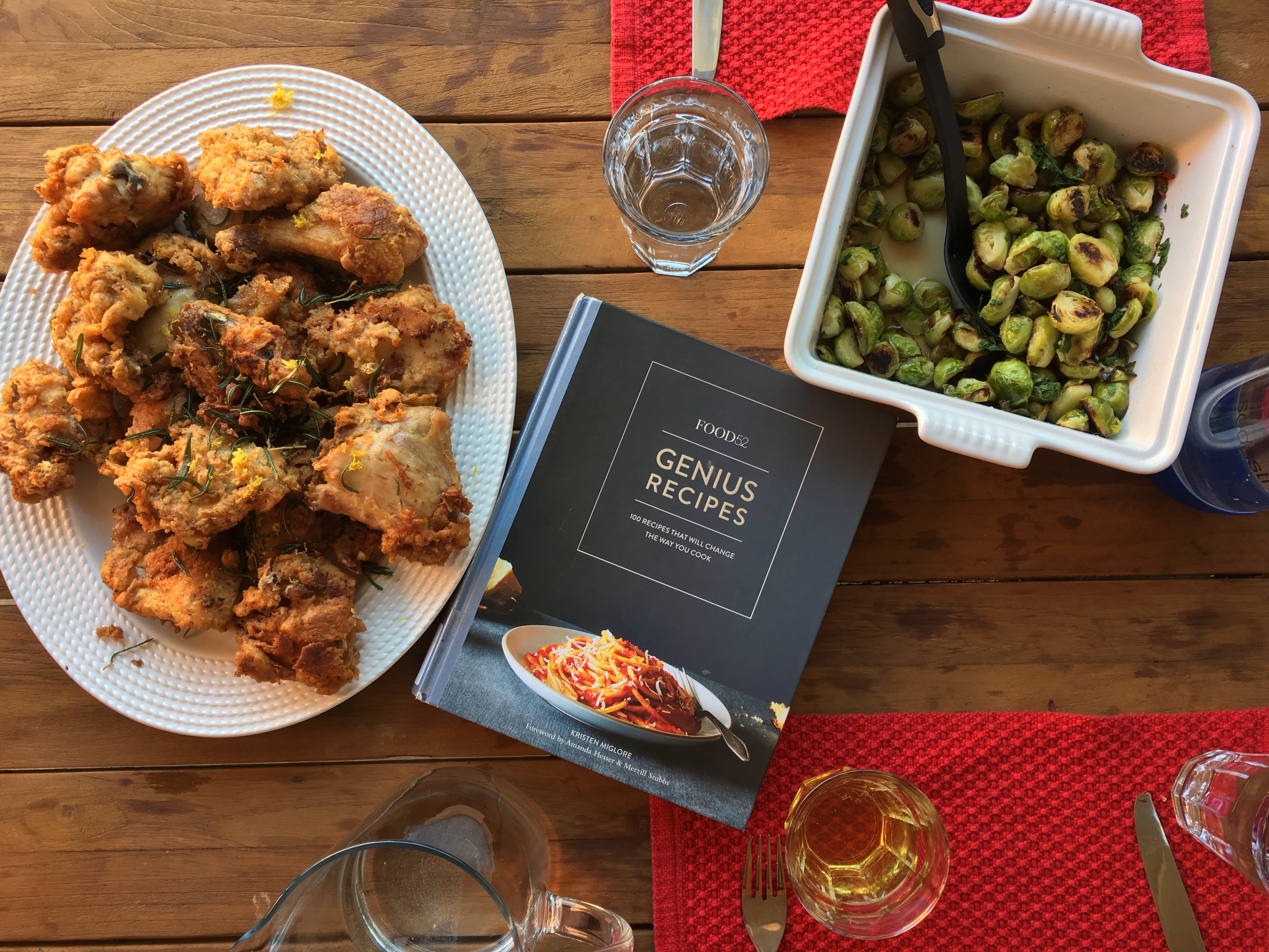 Genius Recipes Cookbook on Dinner table with food