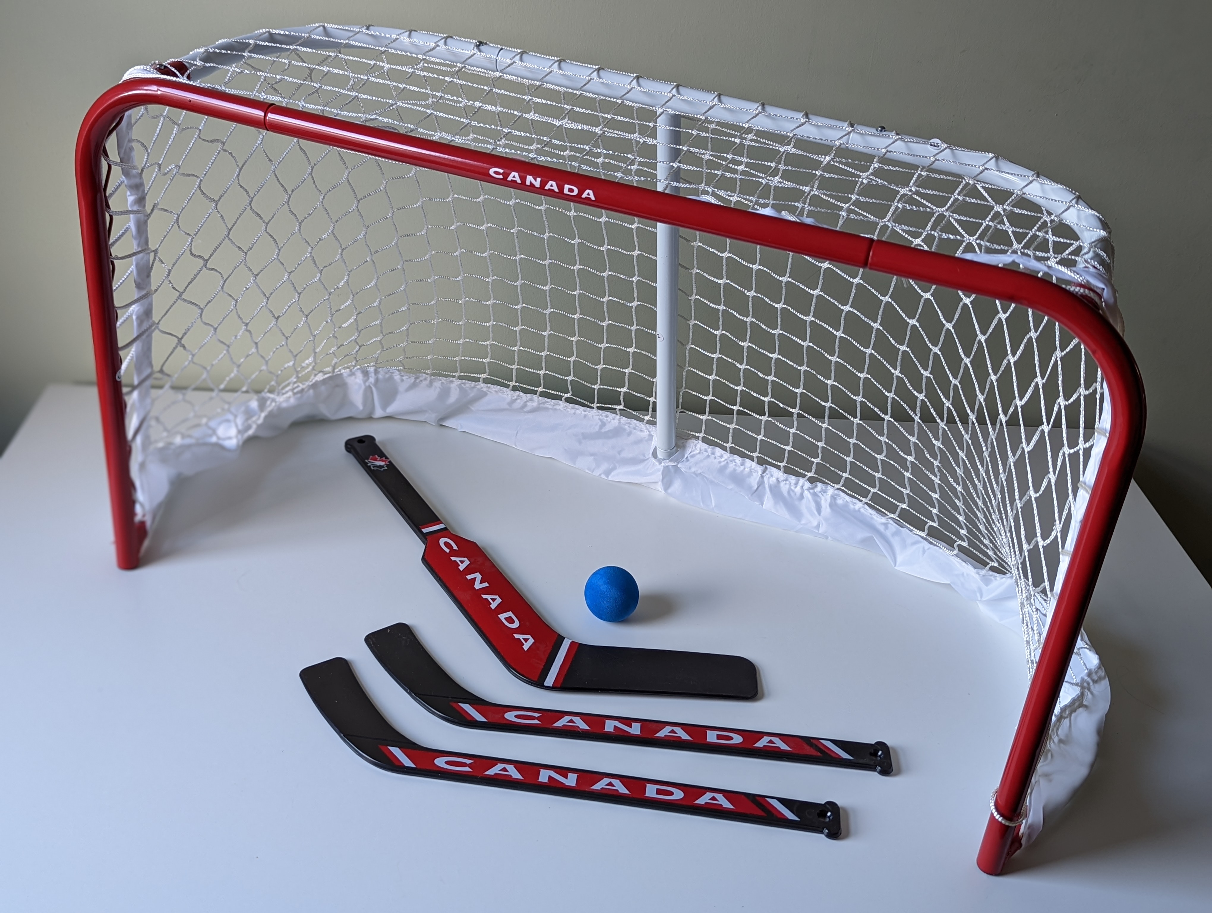 Mini hockey net with three hockey sticks and a ball