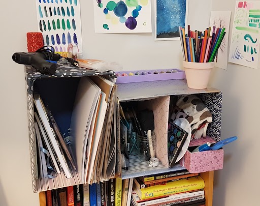 A DIY shelf made from recycled boxes, holding art supplies and books